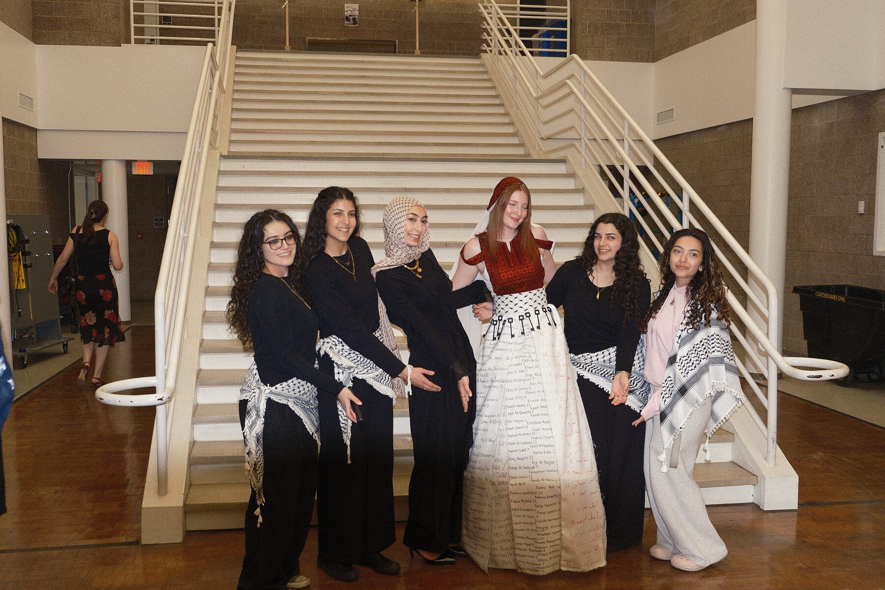 Members in keffiyehs and traditional dress by the staircase at the NOMAS fashion show